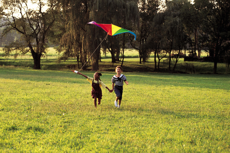 Young girls running in field and flying a kite