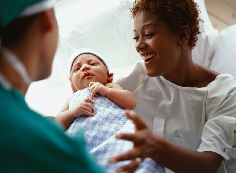 elevated close-up view of a doctor handing a new born baby to the mother