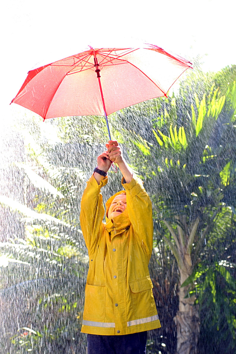 Boy playing in the rain with umbrella