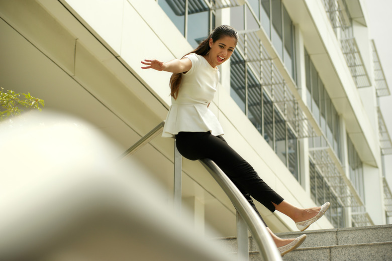 Cheerful Business Woman Going Downstairs Sliding On Rail For Joy