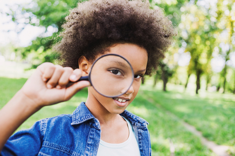 Funny little girl child looking through magnifying glass