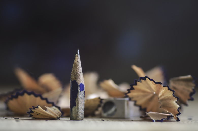 A very short sharpened pencil with shavings and a sharpener