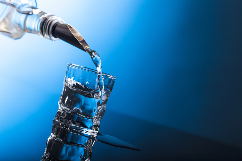 Vodka pouring from the bottle into  glass in a bar.