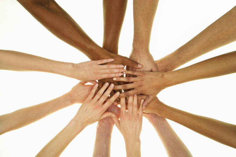 Several people stacking hands on top of each other, overhead view