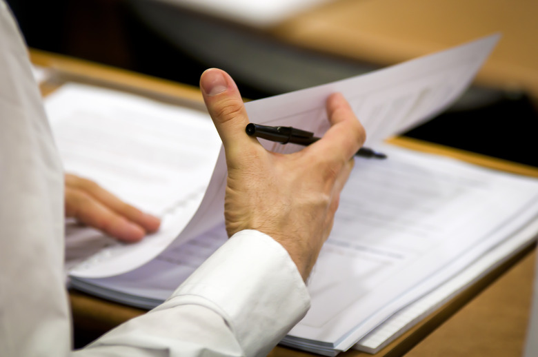 Businessman flipping business papers on a wooden desk