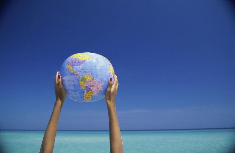 Person holding up a globe at the beach