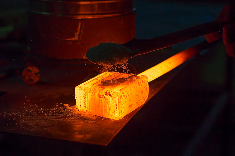 Glowing iron ingot on the table. Hot metal workpiece for the manufacture of Damascus steel.