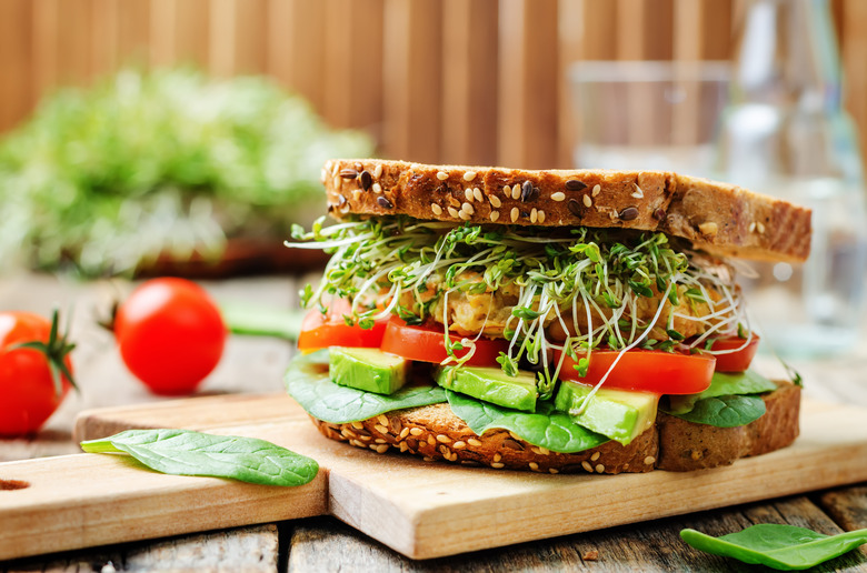 Sandwich on rye with sprouts, avocado, tomato, spinach and chickpea patty