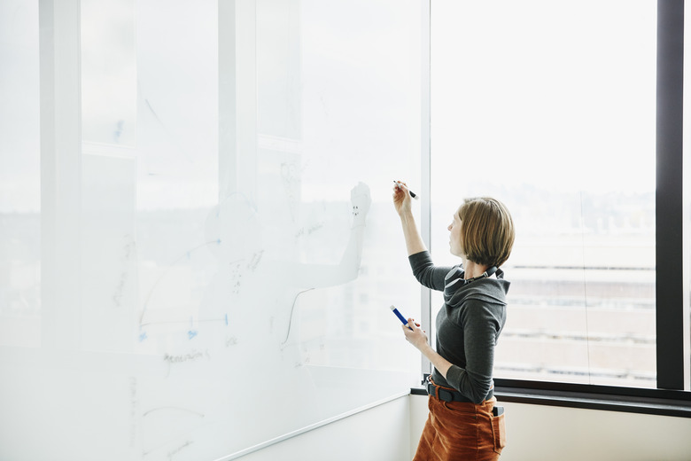 Female scientists working on project data on whiteboard in research lab