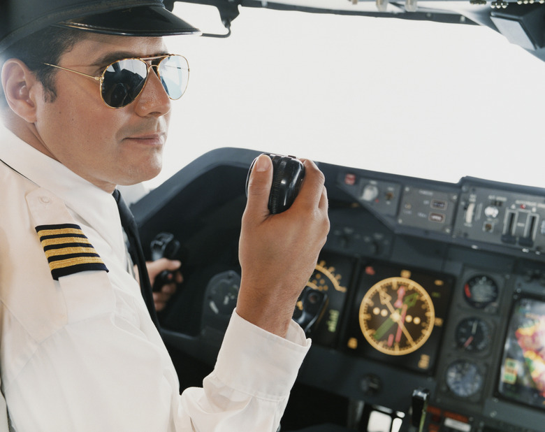 Portrait of a Male Pilot Sitting in the Cockpit Holding a Radio