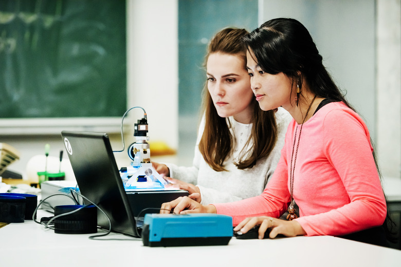 Two Students Focussing On Experiment While Working On Computer