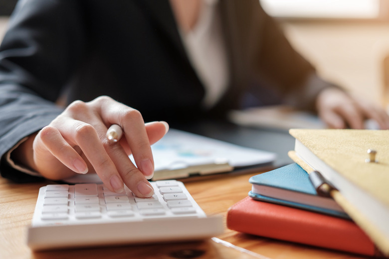 Close up Business woman using calculator and laptop for do math finance on wooden desk in office and business working background, tax, accounting, statistics and analytic research concept