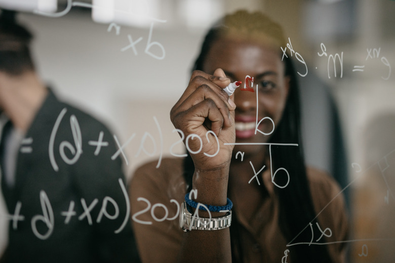 Professor Writing Mathematical Formulas on a glass