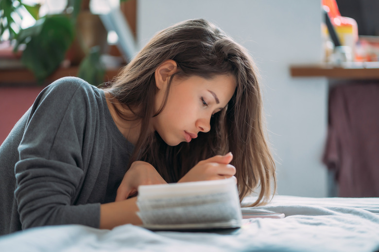 Beautiful exhausted female student preparing for upcoming examination.