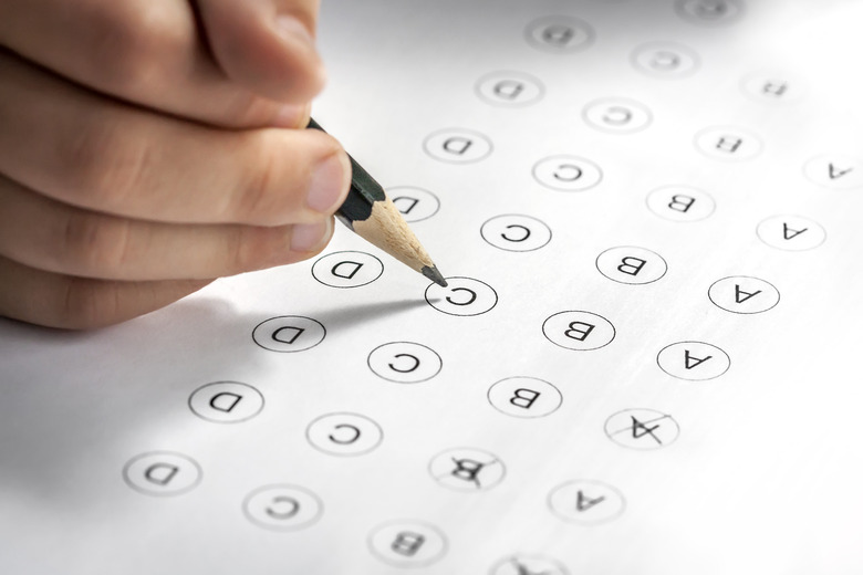 Child's hand filling in a multi-answer test with a pencil