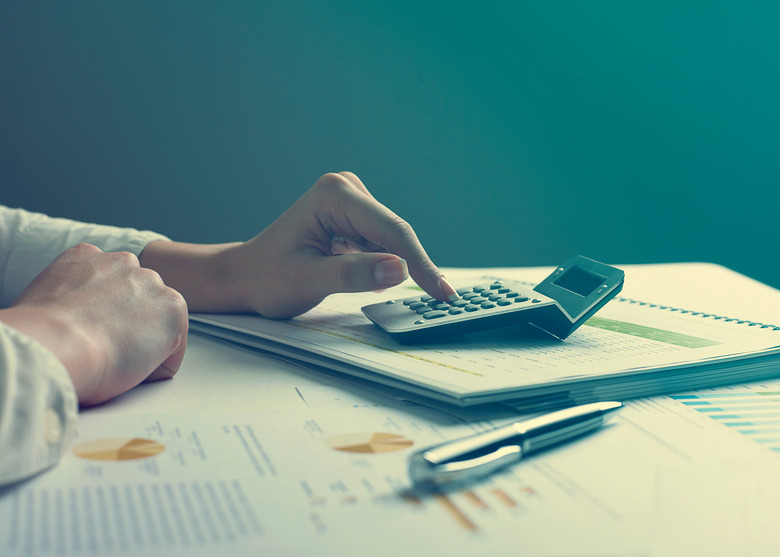 Cropped Hand Of Woman Using Calculator At Table