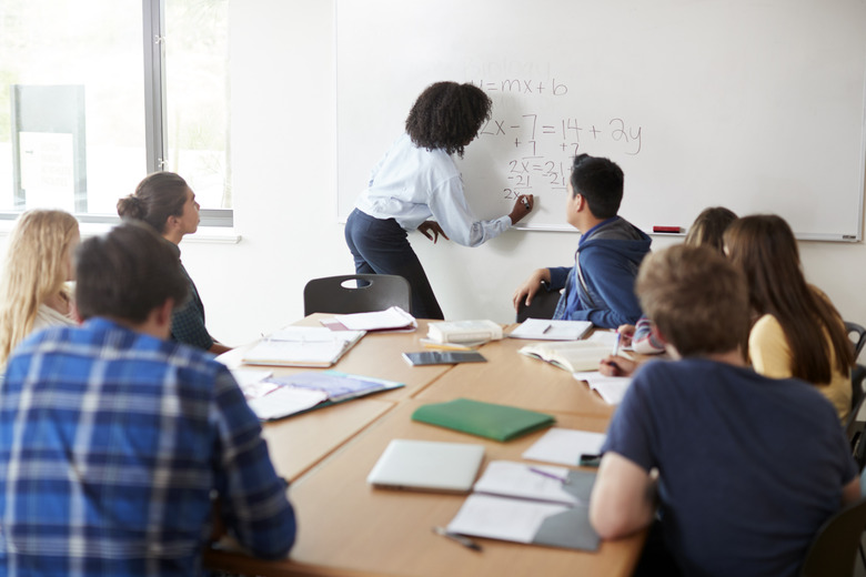 Female High School Tutor At Whiteboard Teaching Maths Class