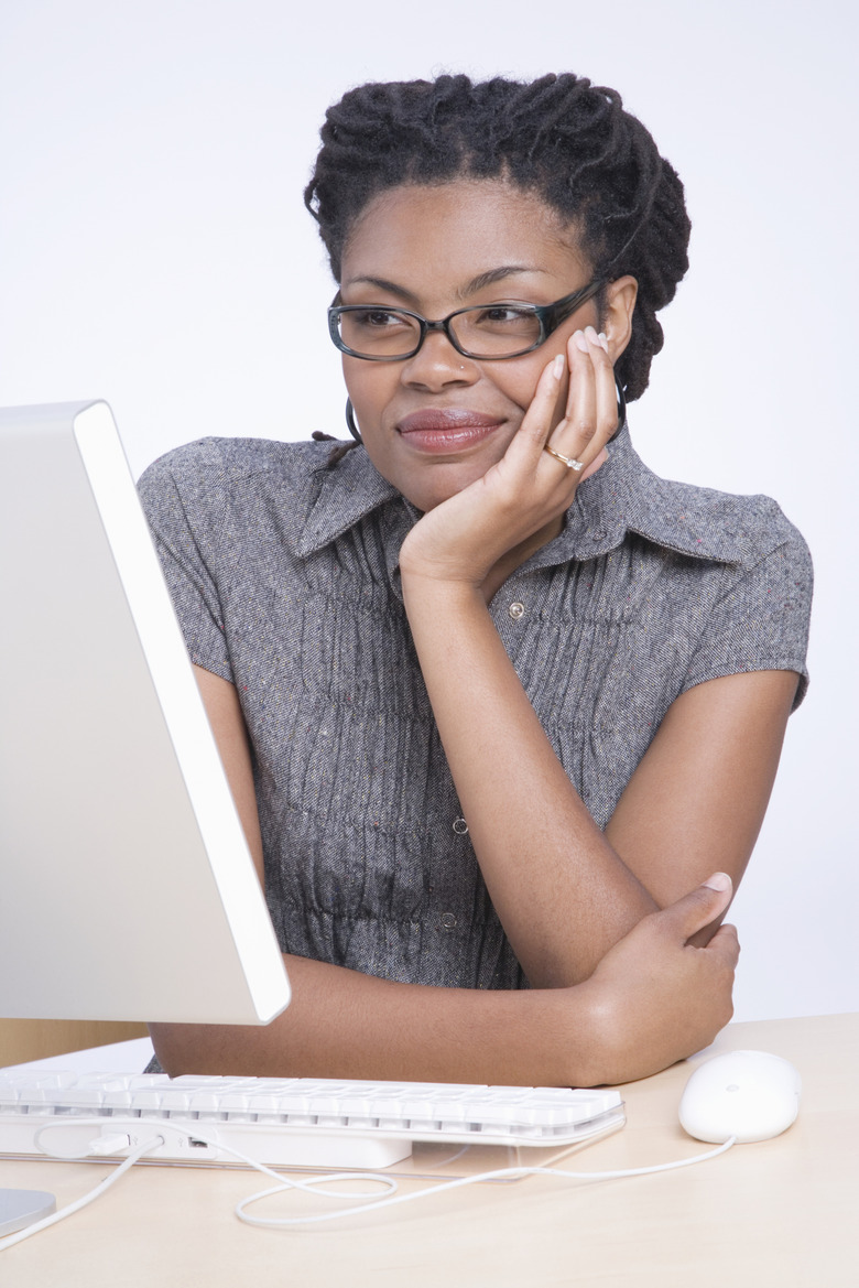 Young woman sitting at desk using computer, smiling