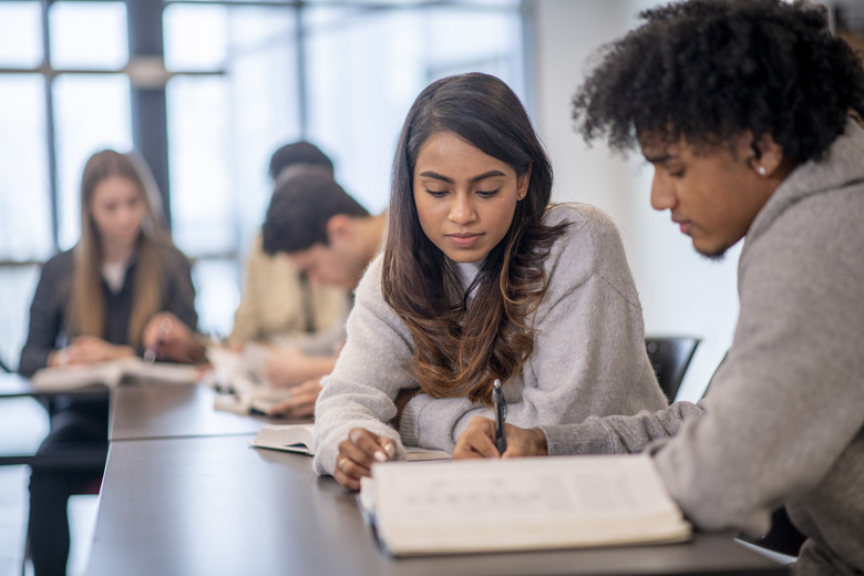 University Students Sharing a Textbook in Class stock photo