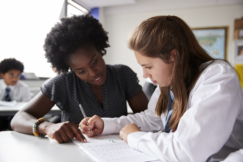 High School Tutor Giving Female Student Wearing Uniform One To One Tuition At Desk