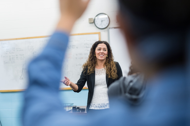 Ethnic teacher points to one of her students with a raised hand