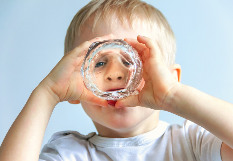 Happy cheerful boy is drinking from a glass,