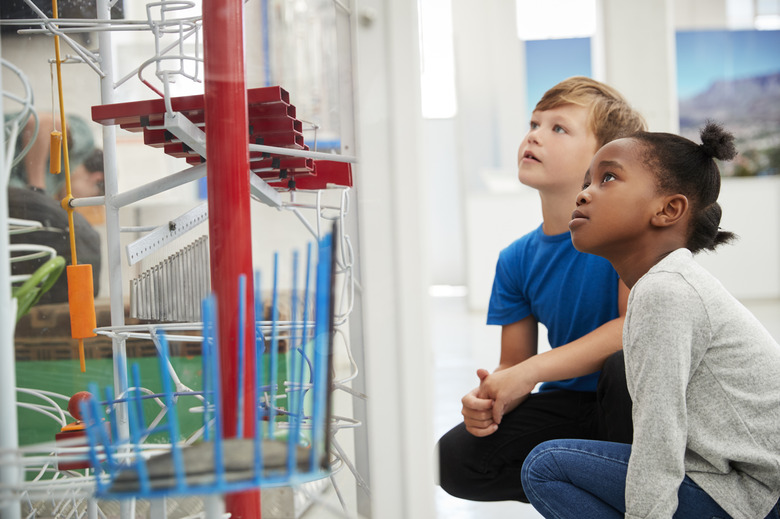 Two kids kneeling and looking at a science exhibit