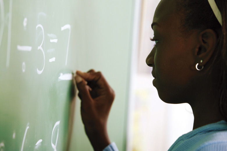 Girl writing math problem on chalkboard