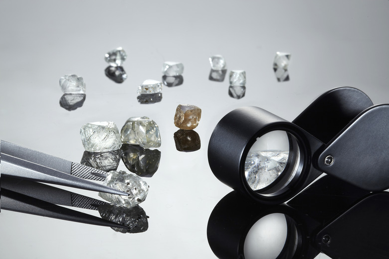 Uncut diamonds with tweezers and loupe