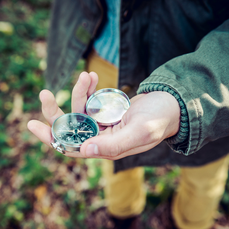 Young hiker looking a compass in the woods