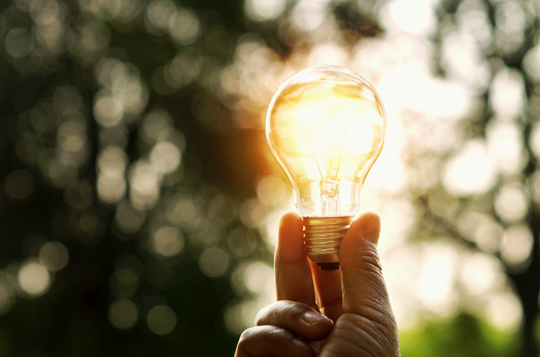 hand holding light bulb and sunset in nature, power energy concept