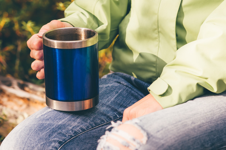 Touristic tea thermal cup in woman hand Travel Lifestyle