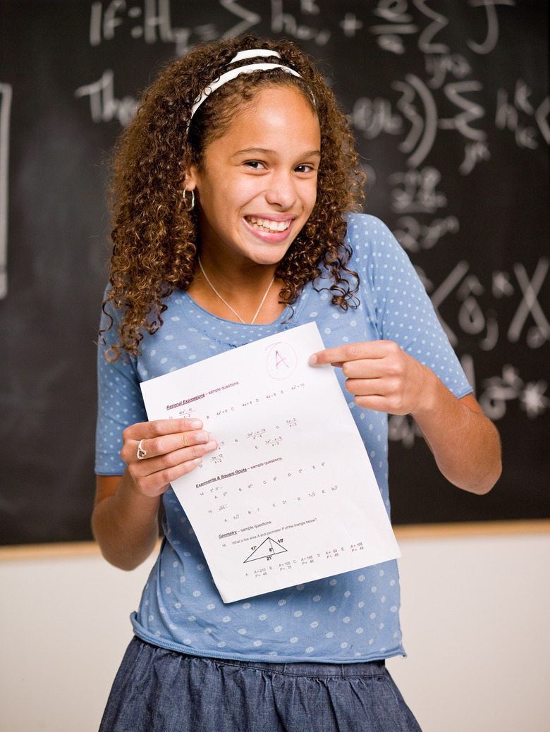 Smiling teenage girl student holding test with perfect grade