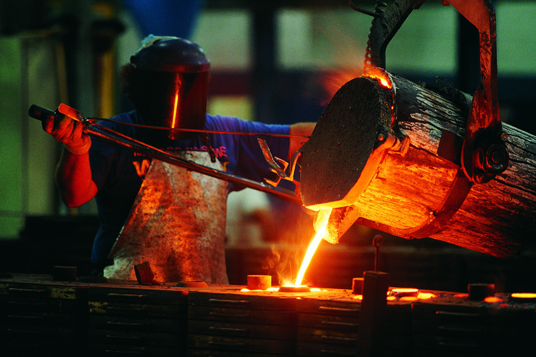 Foundry worker pouring steel