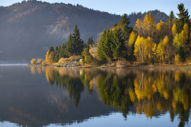 Lovely autumnal landscape with fog over the lake.