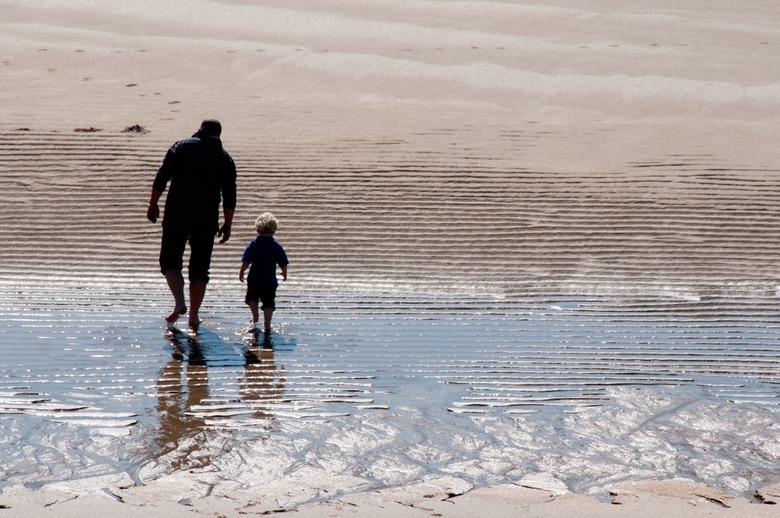 Father and sun walking on the sand in the sunshine.