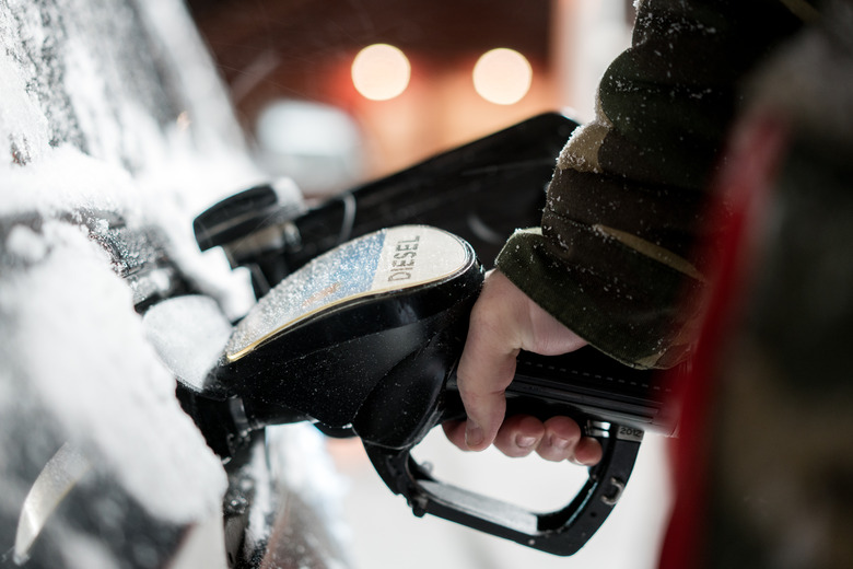 Man with fuel hose nozzle tanking car in winter