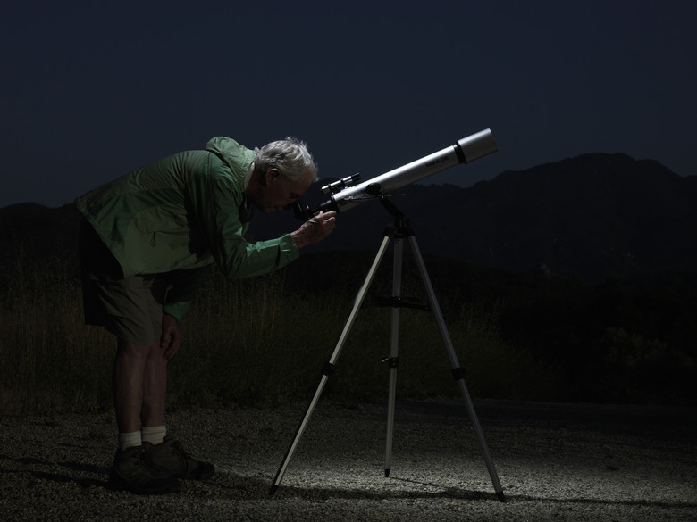 Mature man looking through telescope