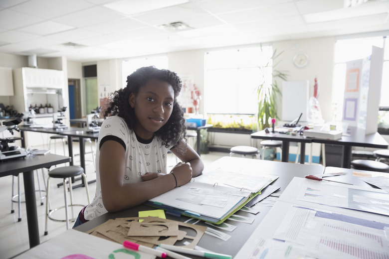 Portrait confident girl middle school student working on science project in classroom