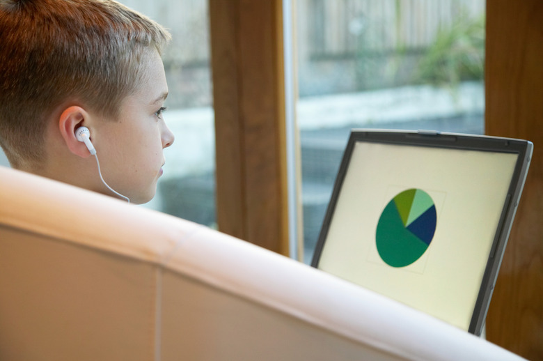 Boy (7-9) using laptop and listening to earphones