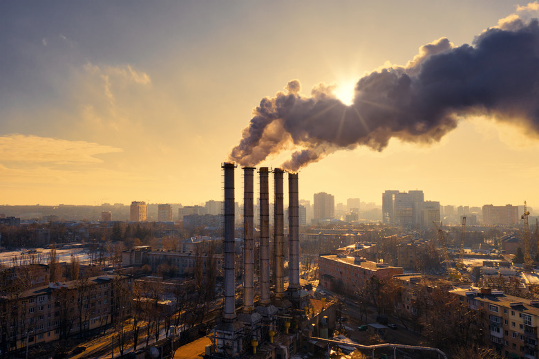 Pipes with yellow toxic smoke in front of the cityscape