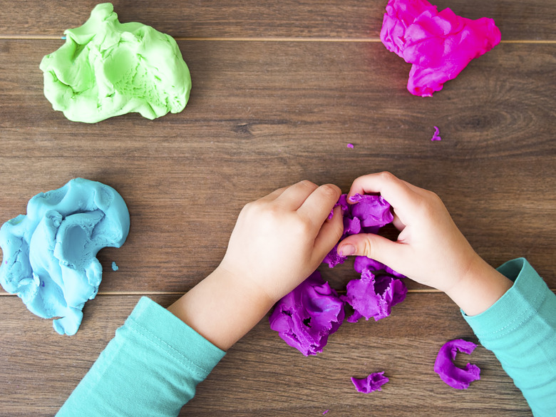 Kid playing with a modeling compound on a dark background