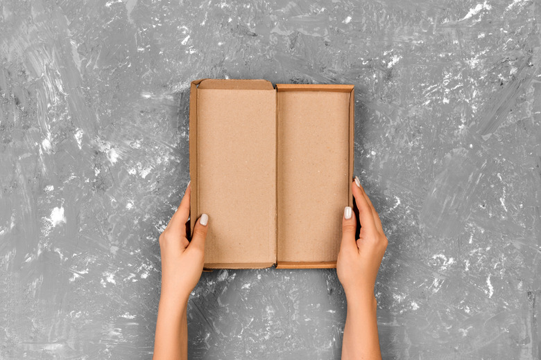 Cropped Hands Of Woman Holding Empty Cardboard Box On Table