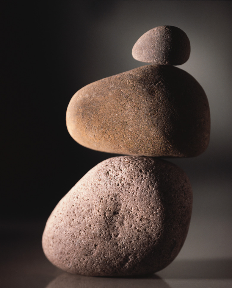 Rocks stacked on each other while standing on a reflective surface with a gray and black background