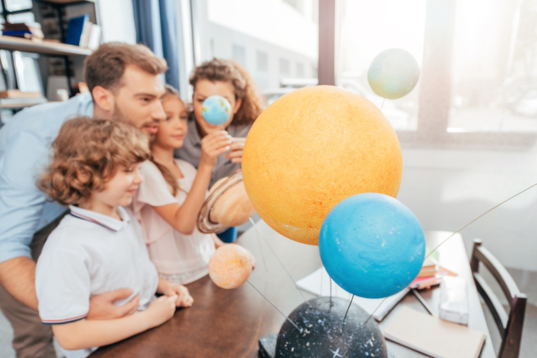 young happy family making solar system model for school project