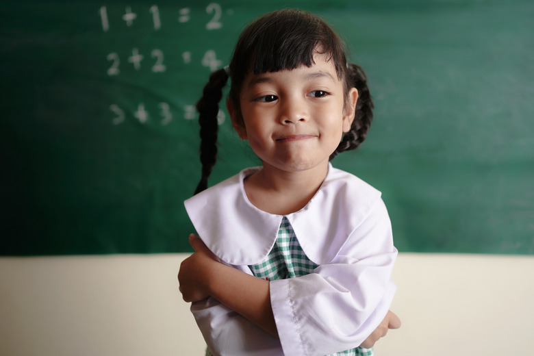 preschooler in front of math problems on a blackboard