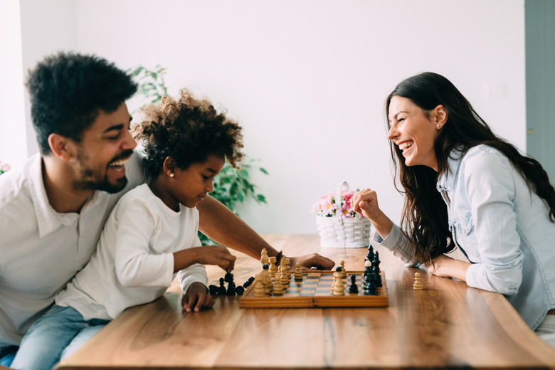 Happy family playing chess together at home