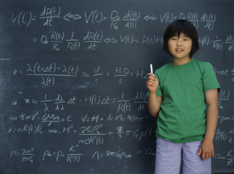 Portrait of girl holding chalk in front of chalkboard