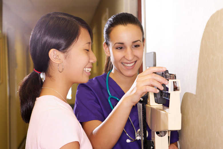 A nurse weighs a teen girl at the doctor's office