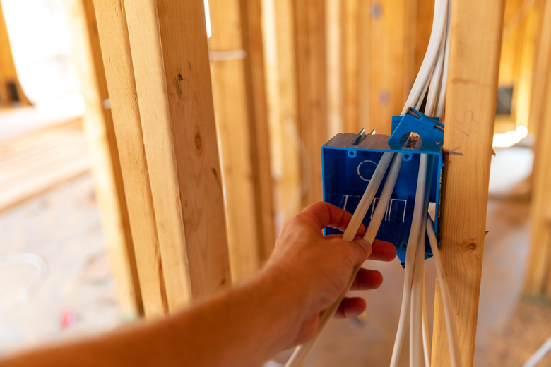 Hand installing electrical wiring in new home under construction